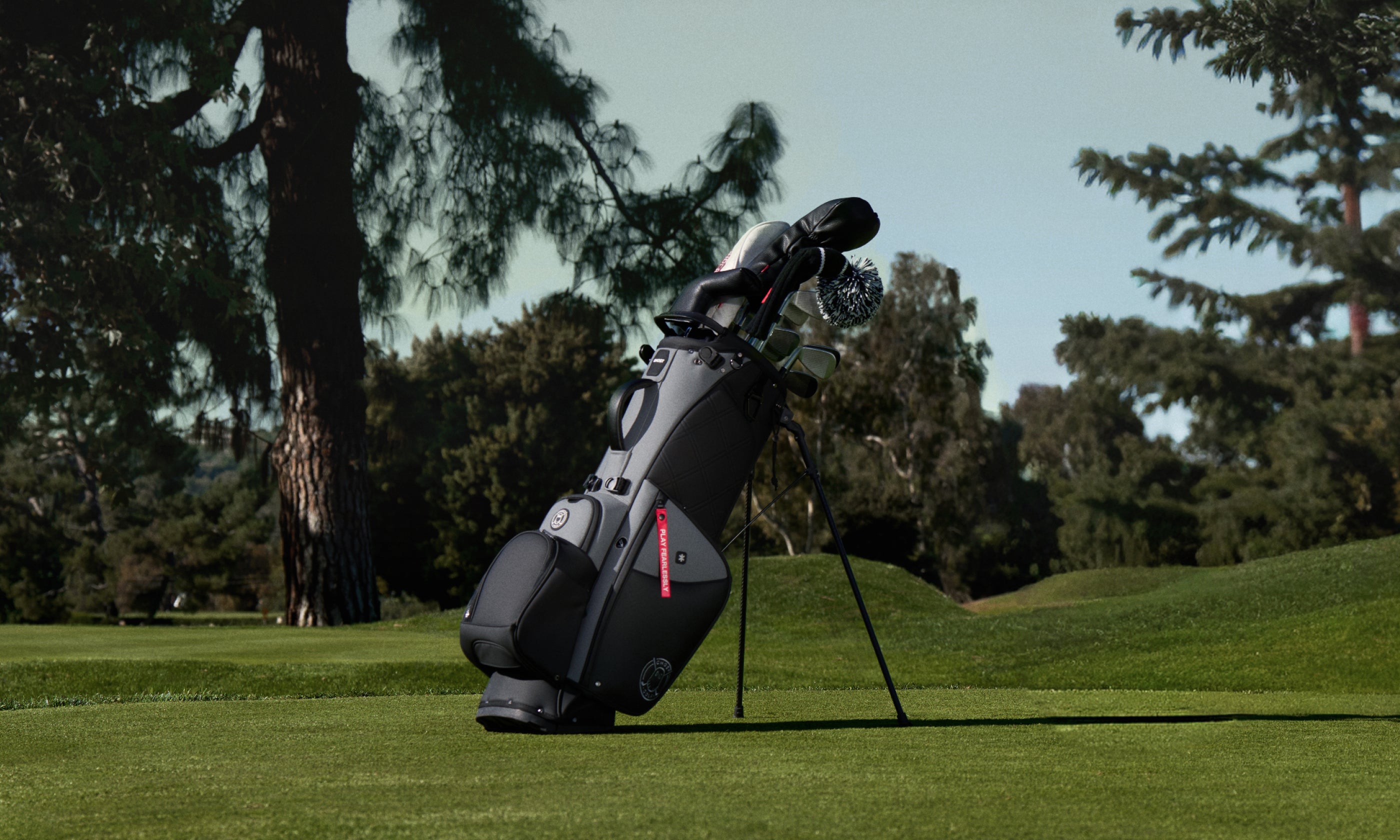 Golf bag with clubs on a grassy area with trees in the background