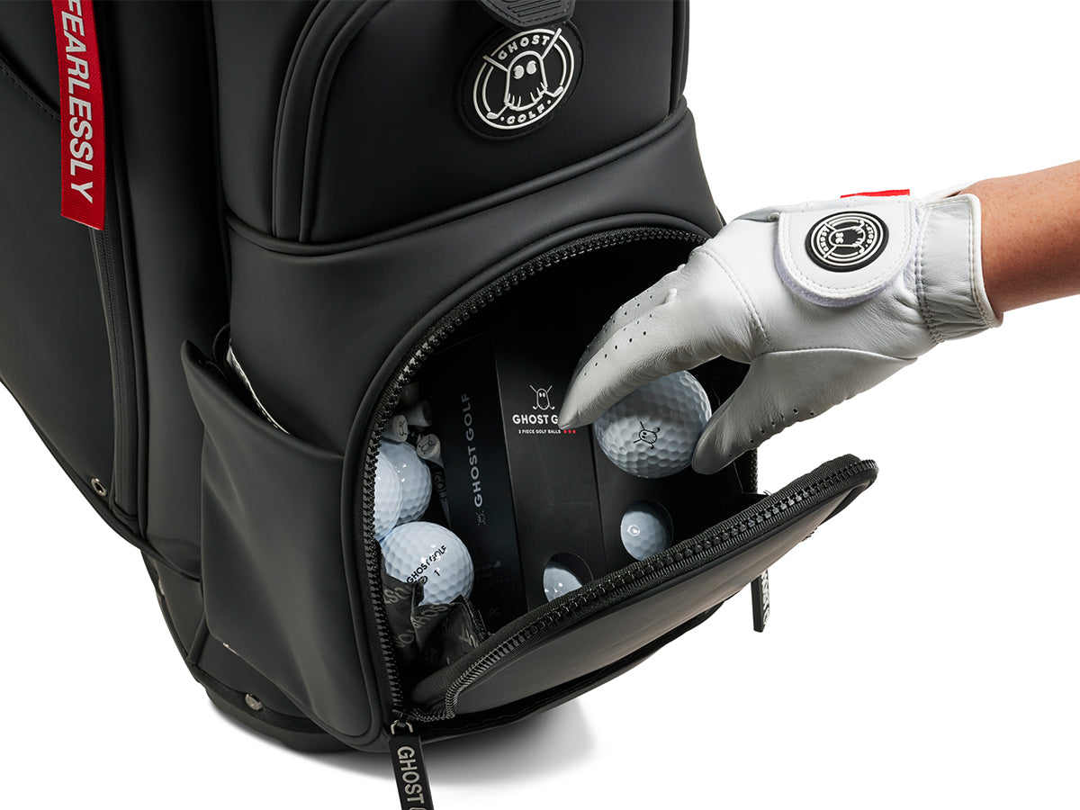 Black golf bag with golf balls and a hand wearing a white glove reaching in, featuring the 'GHOST GOLF' brand.