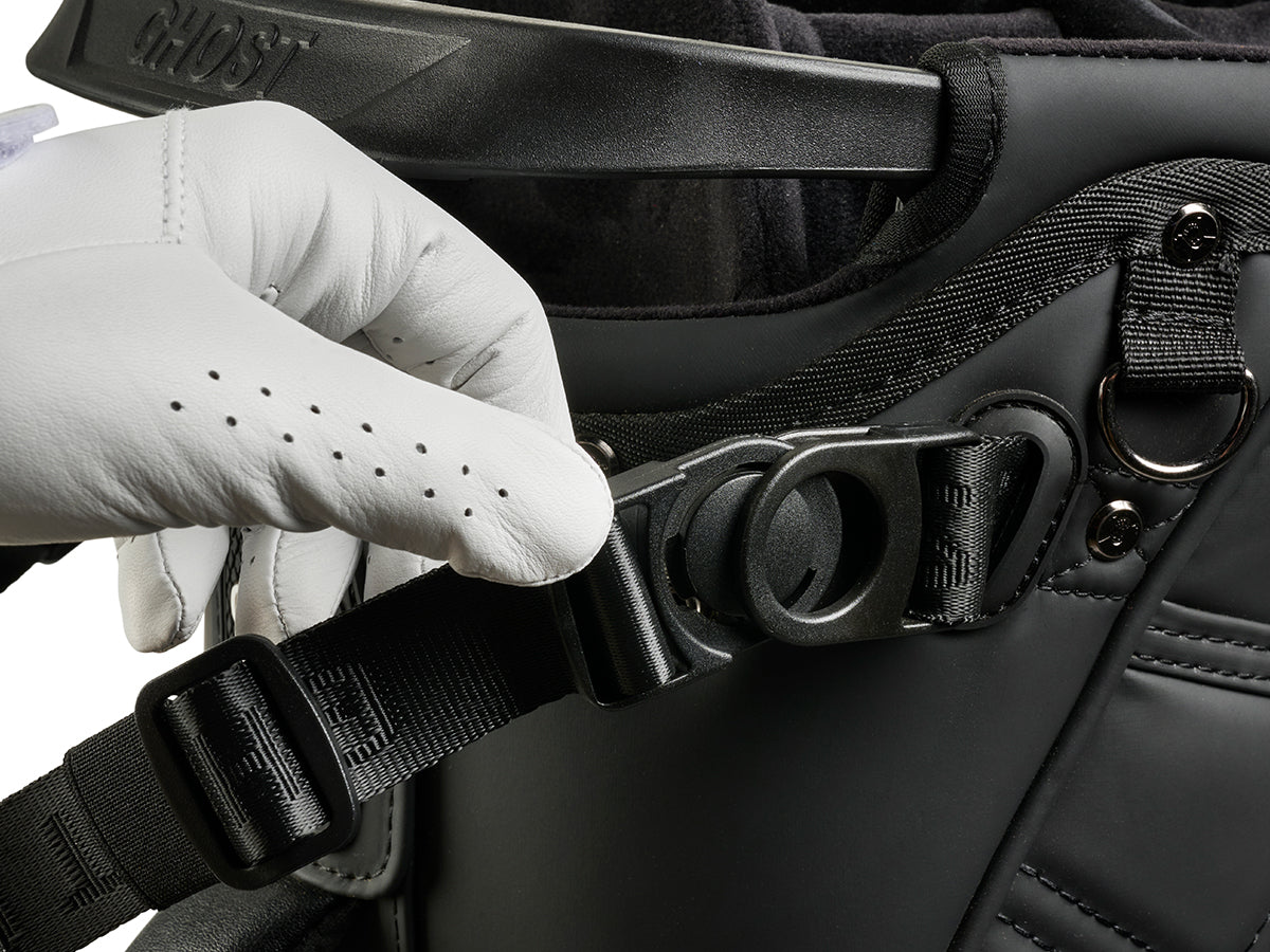 Hand wearing a white glove adjusting a golf bag strap