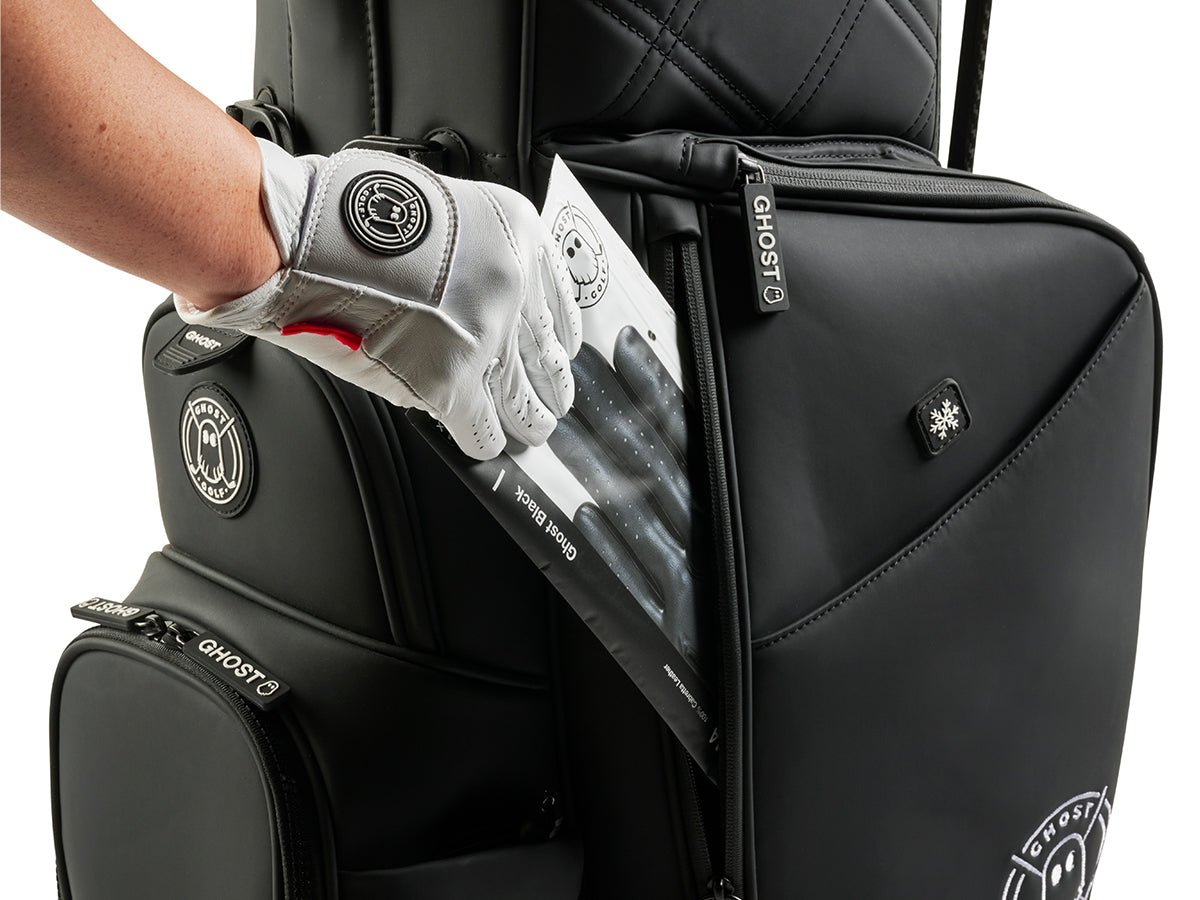 Black golf bag with 'GHOST' branding, showing a glove being put inside a pocket