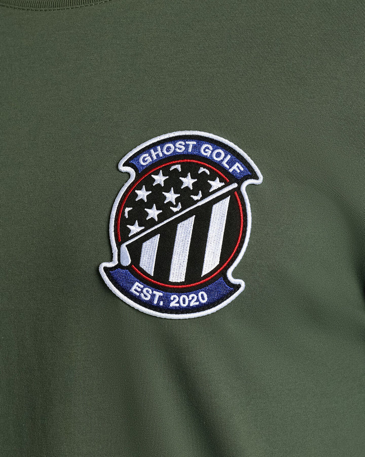 Closeup Shot of Forest Shadow Flag Flight Tee showcasing front emblem graphic Ghost Golf Hit #color_forest shadow