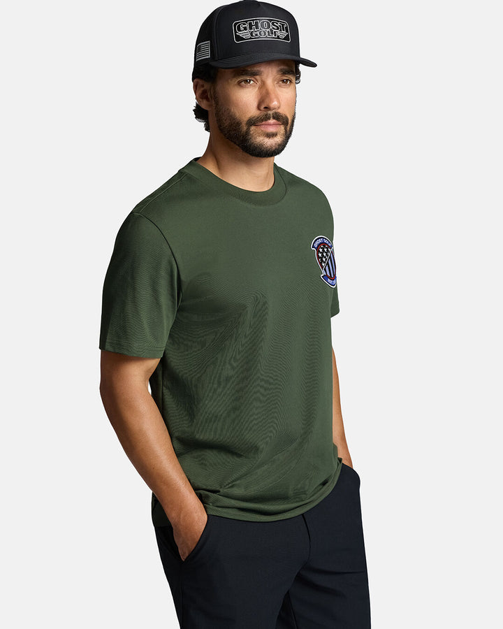White male model wearing Black Flight Logo Hat wearing a geen t-shirt and black pants with hand in pocket looking towards his right #color_black