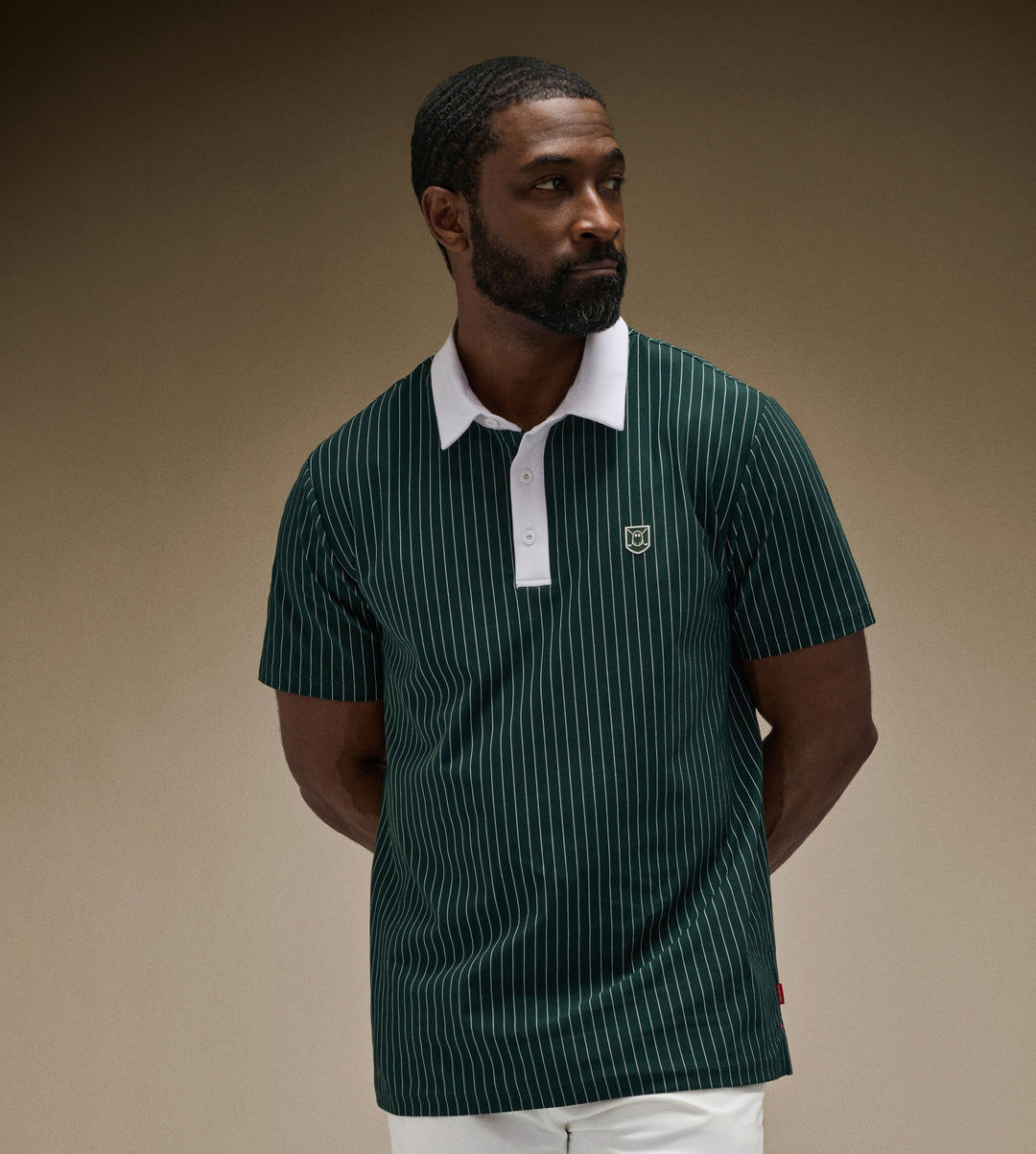 Black Male Model in brown studio setting wearing green striped polo with white shorts