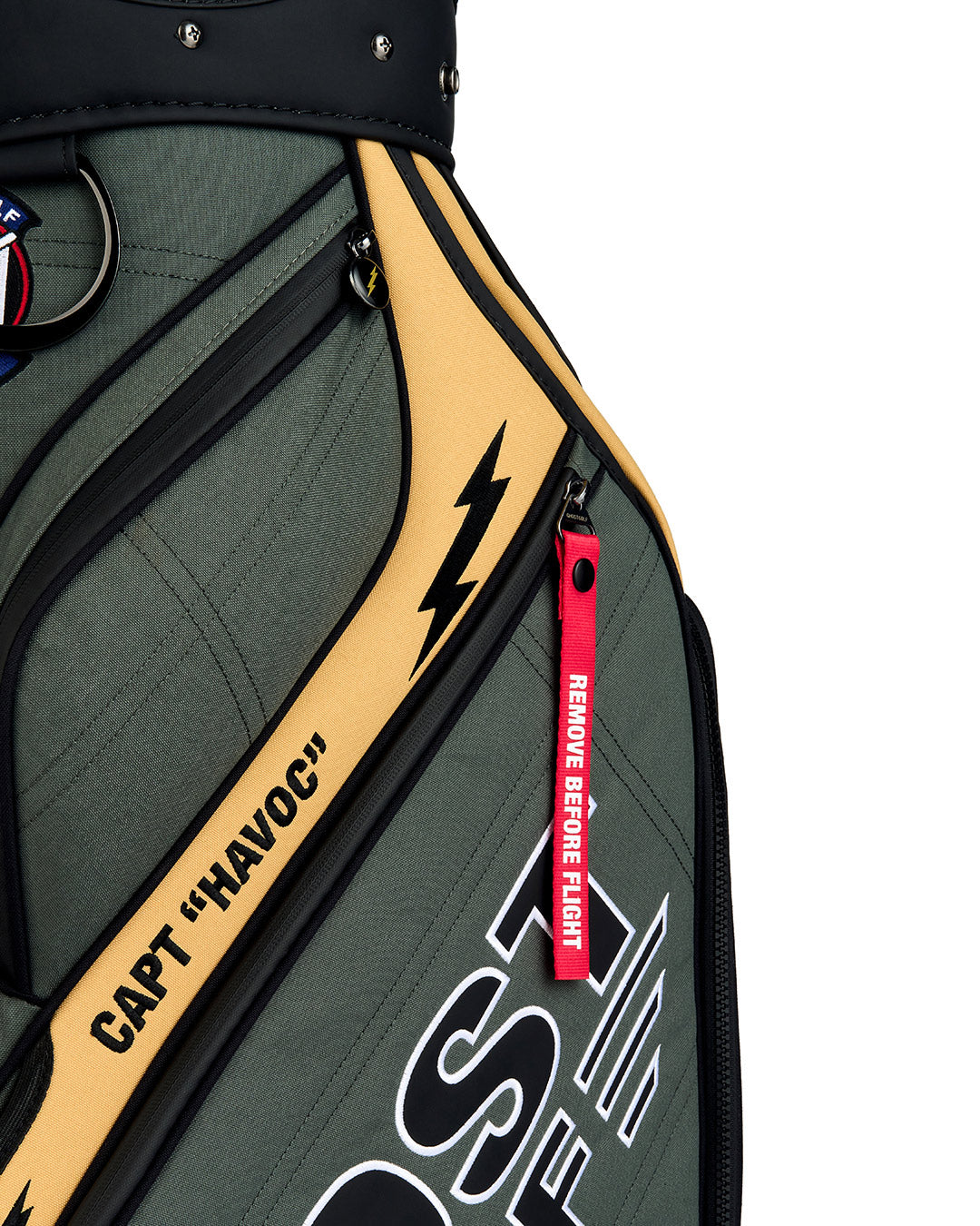 Detail shot of the G-Suit Staff Bag showcasing the signature red "Remove Before Flight" tab and Capt Havoc branding. Close-up image highlighting the premium materials, embroidered details, and aviation-inspired design elements.