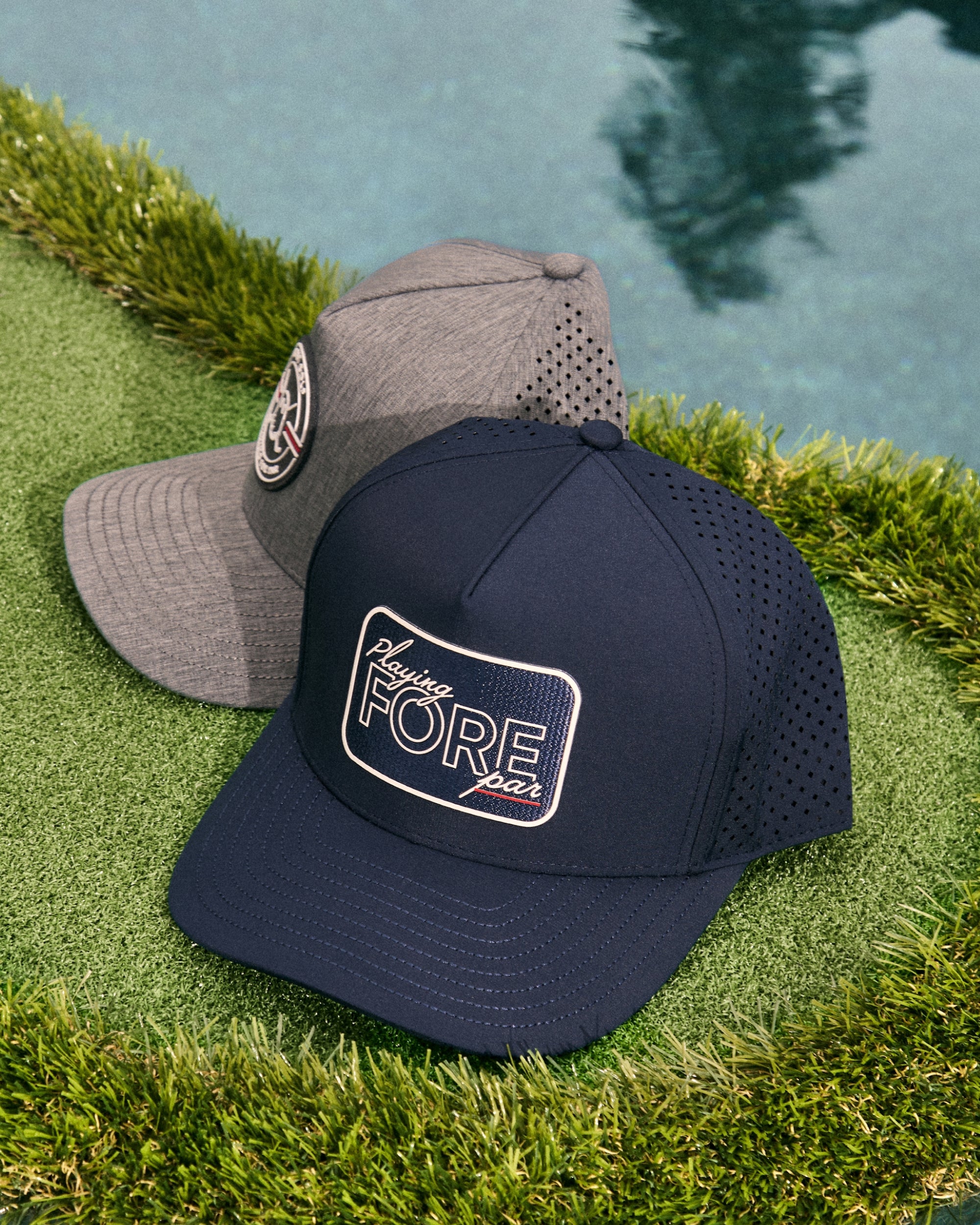 Two hats rest on a golf-style mat floating in a pool, creating a stylish golf-inspired display. Golf accessories are arranged around the mat, adding to the relaxed and elevated poolside lifestyle aesthetic.