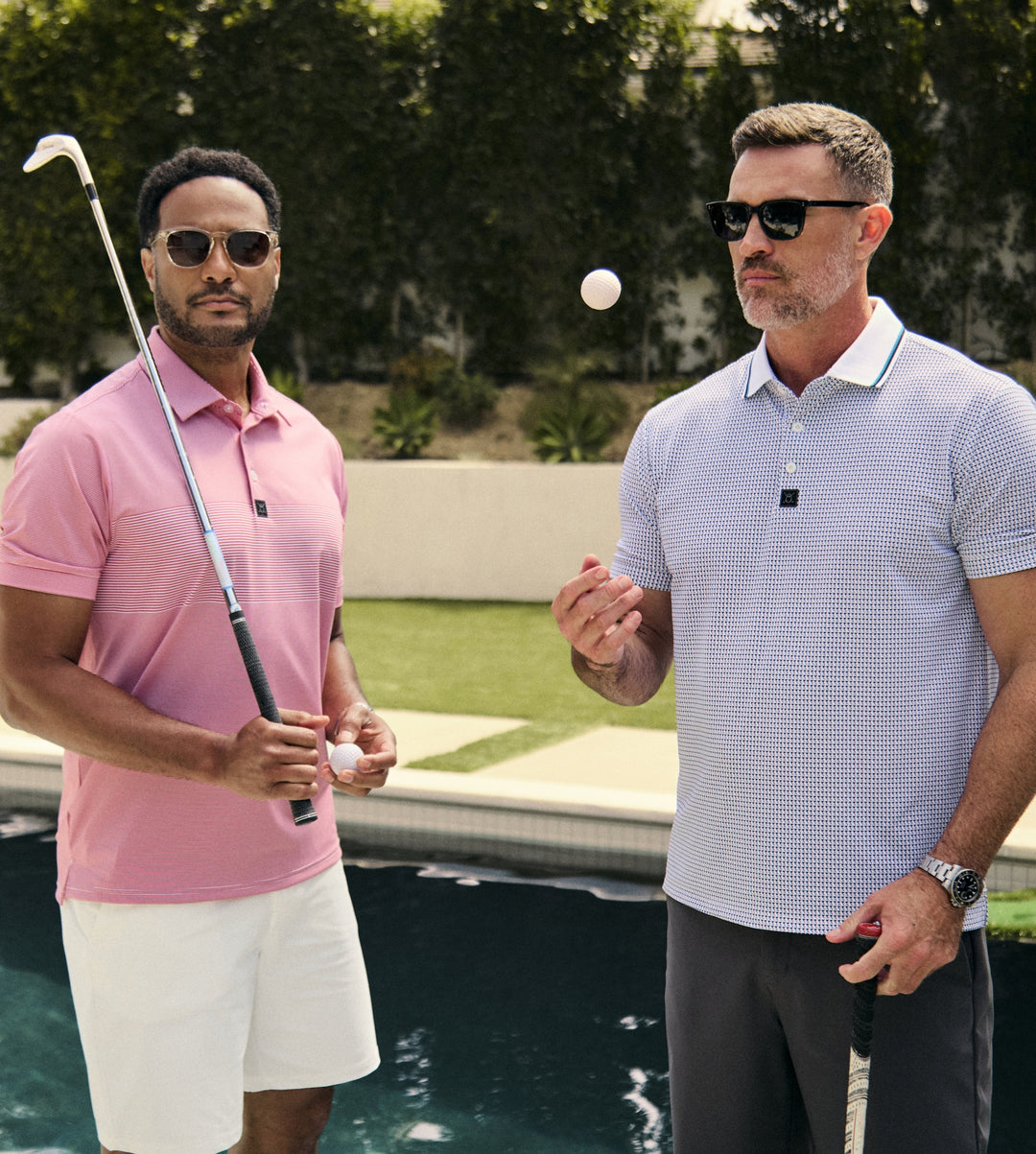 Two male models stand by the pool in a relaxed, confident pose. One model holds a golf club and golf ball, while the other tosses a golf ball into the air, creating a casual and playful poolside scene.