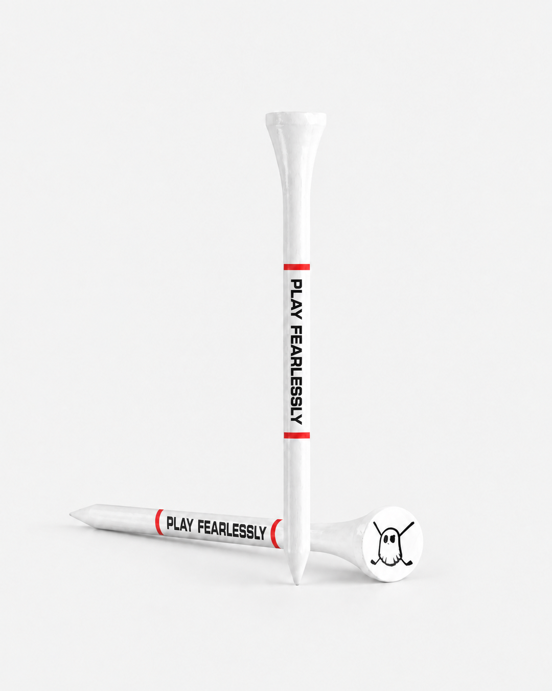 Two white tees with red bands and black 'PLAY FEARLESSLY' text, shown on a clean light gray studio background. One tee is upright and one lies on its side, with a white club head resting on the tee base.