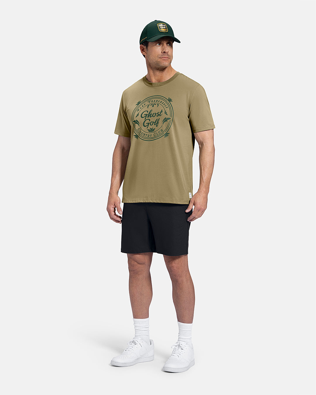 Full Body Front View of Sand Patrons Club Badge Tee on white male model wearing black shorts and white shoes and green hat #color_sand