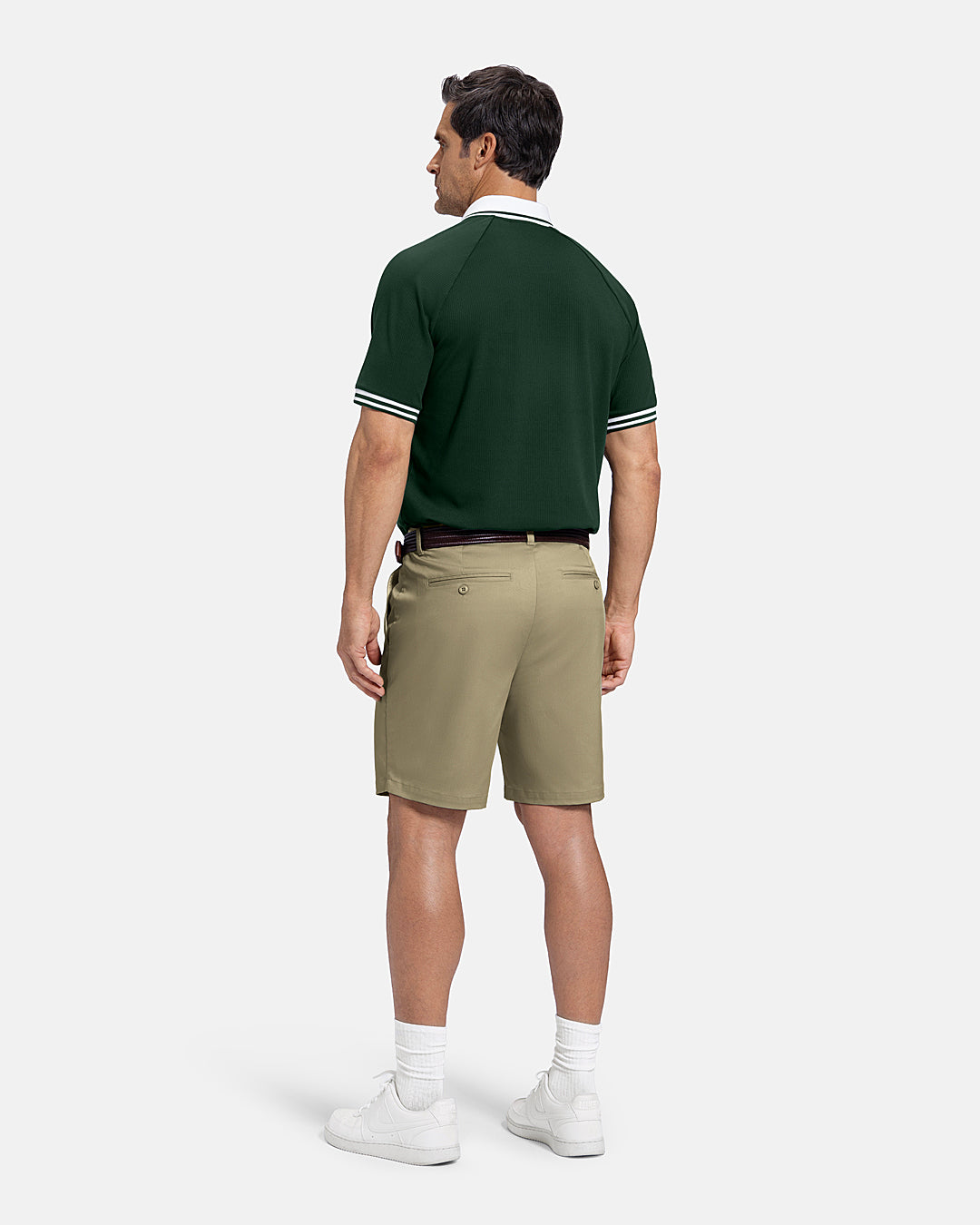 Full Body Back View of Sand Patrons Pleated Short on white male model wearing green polo brown belt and white shoes with polo tucked in shorts #color_sand