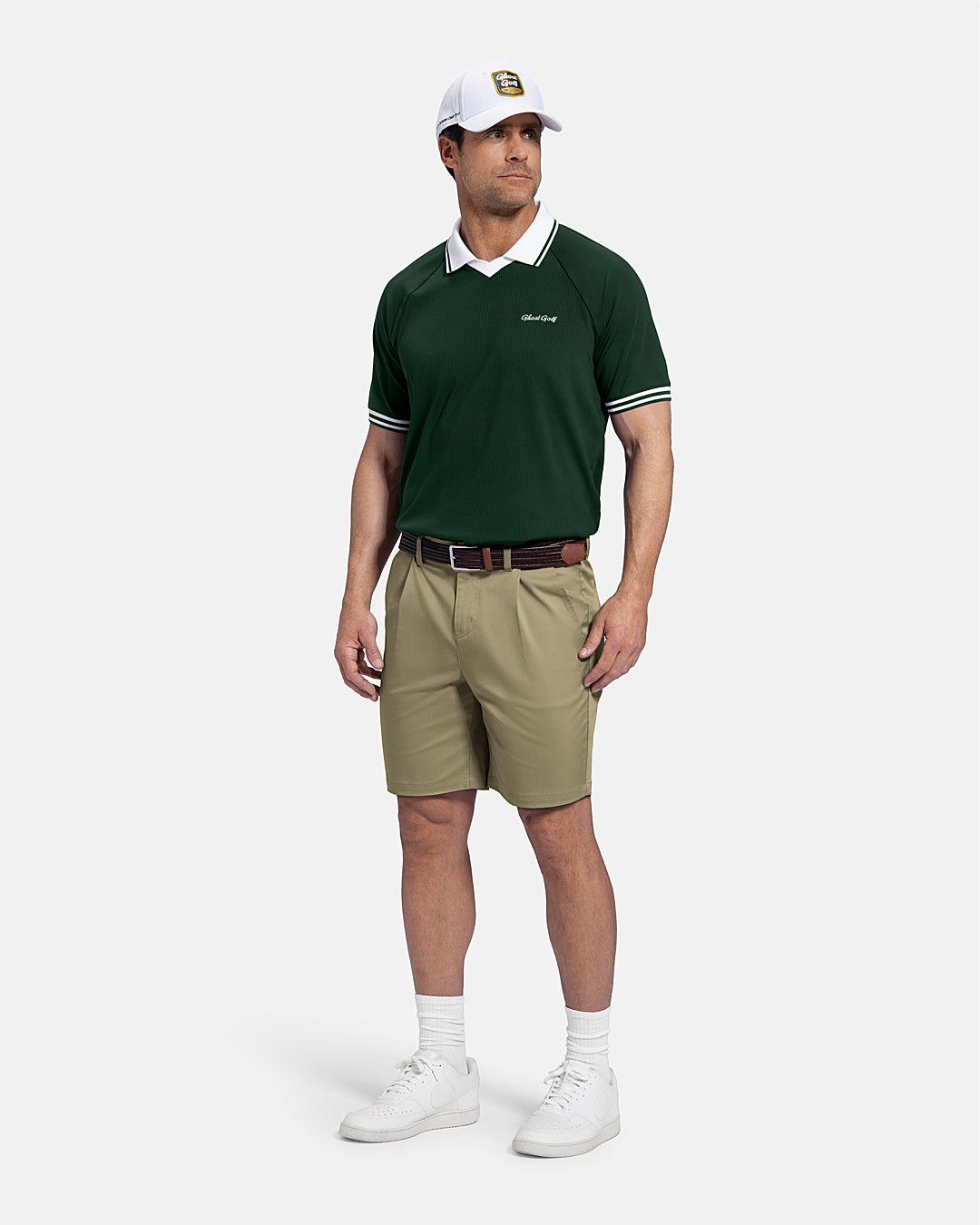 Full Front Back View of Sand Patrons Pleated Short on white male model wearing green polo brown belt and white shoes and white hat with polo tucked in shorts #color_sand