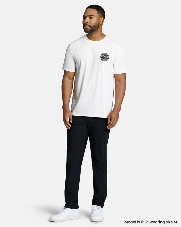 Full Body Front Shot of Black Male Model Wearing White Qualifier Fore Par Tee with black pants and white shoes. #color_white
