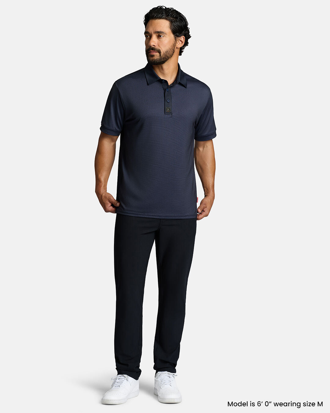 Full Body Front Shot of White Male Model Wearing Dark Navy Qualifier Grid Polo with black pants and white shoes. Polo is untucked. #color_dark-navy