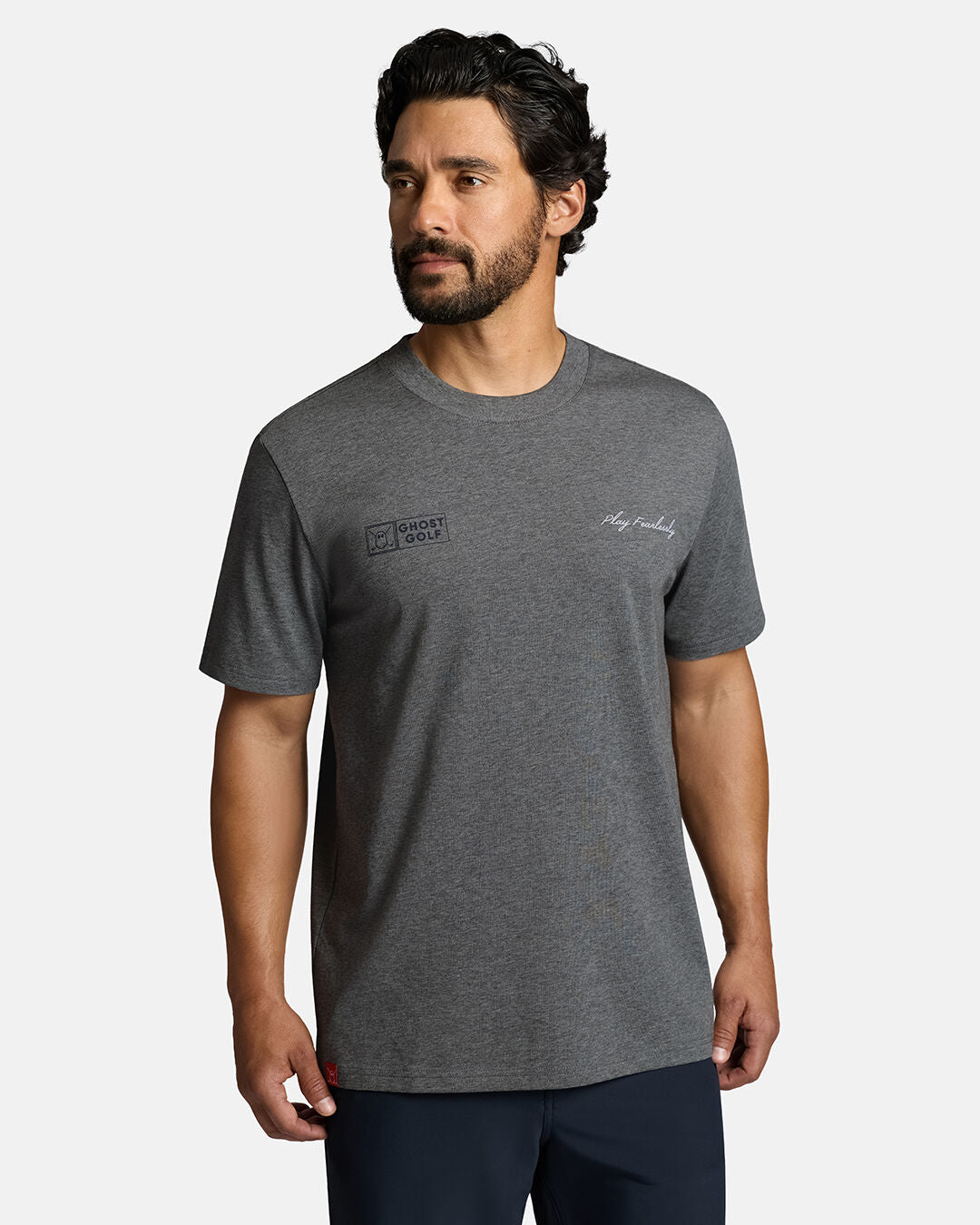 Top Front Body Shot of White Male Model Wearing Grey Qualifier Player Tee show casing play fearlessly and ghost golf hit on each side of the chest. Play fearlessly on left and ghost golf on right. Model is wearing grey shorts #color_heather-grey