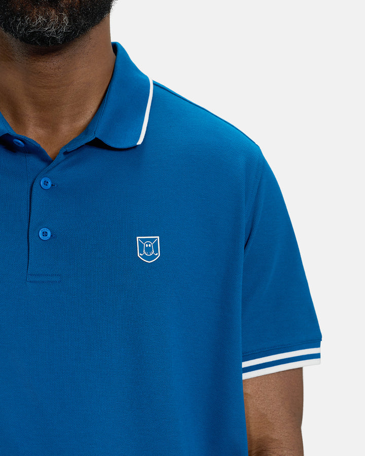 Front Closeup View of Royal Blue Spectator Tipped Collar Polo on Black Male Model with Ghost Icon Crest #color_royal-blue
