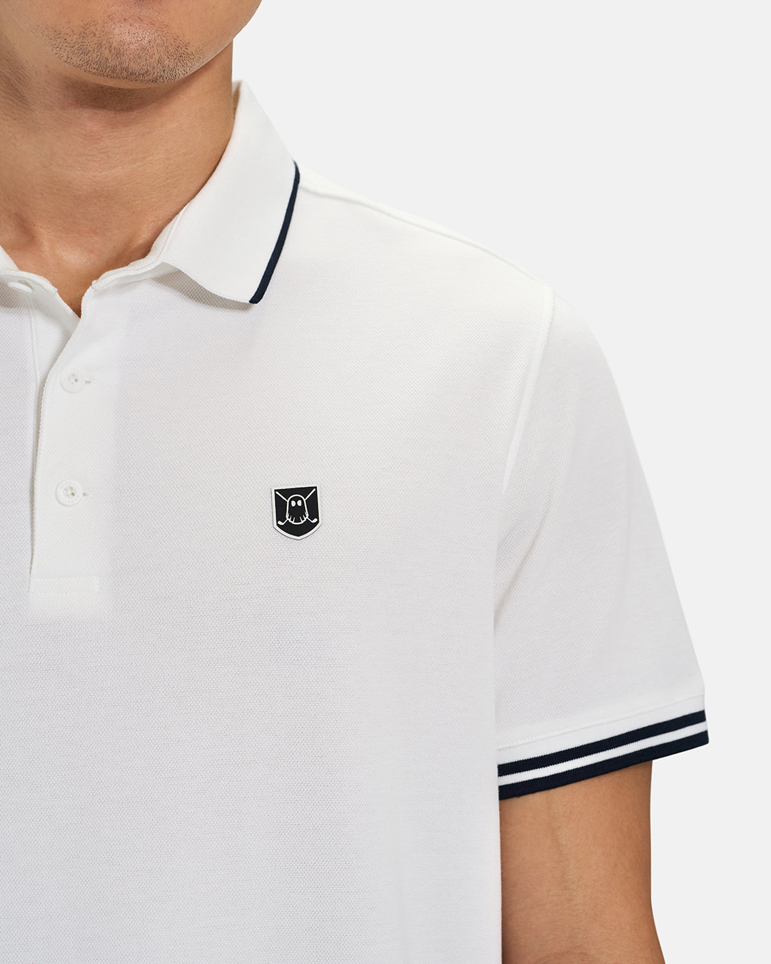 Front Closeup View of White Spectator Tipped Collar Polo on Asian Male Model with Ghost Icon Crest #color_white