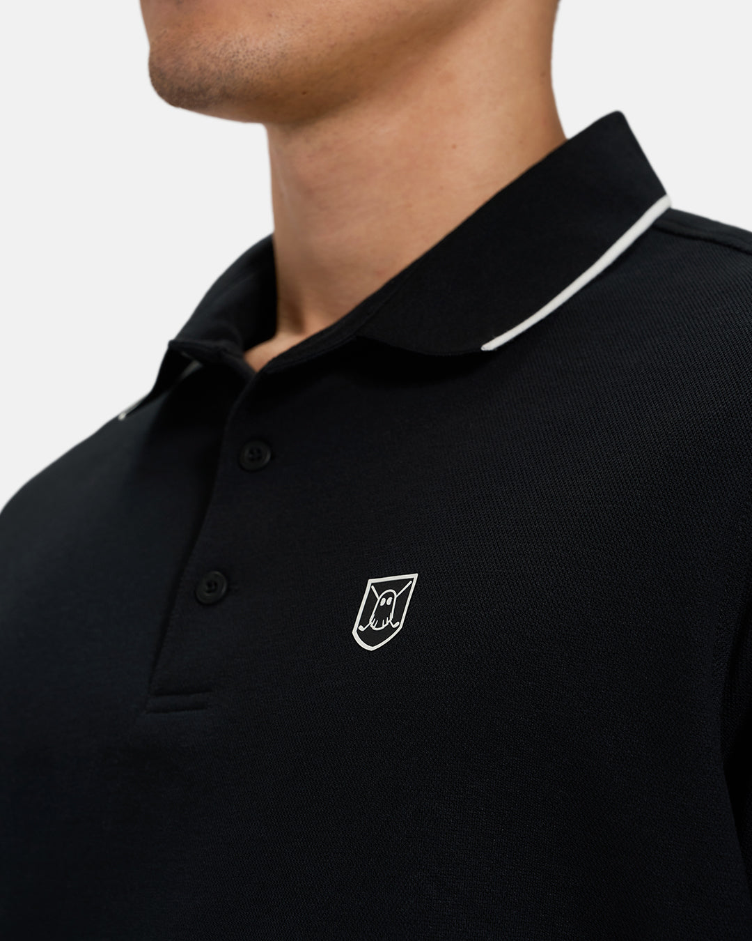 Front Closeup View of Black Spectator Tipped Colllar Polo on Asian Male Model with Ghost Icon Crest #color_black