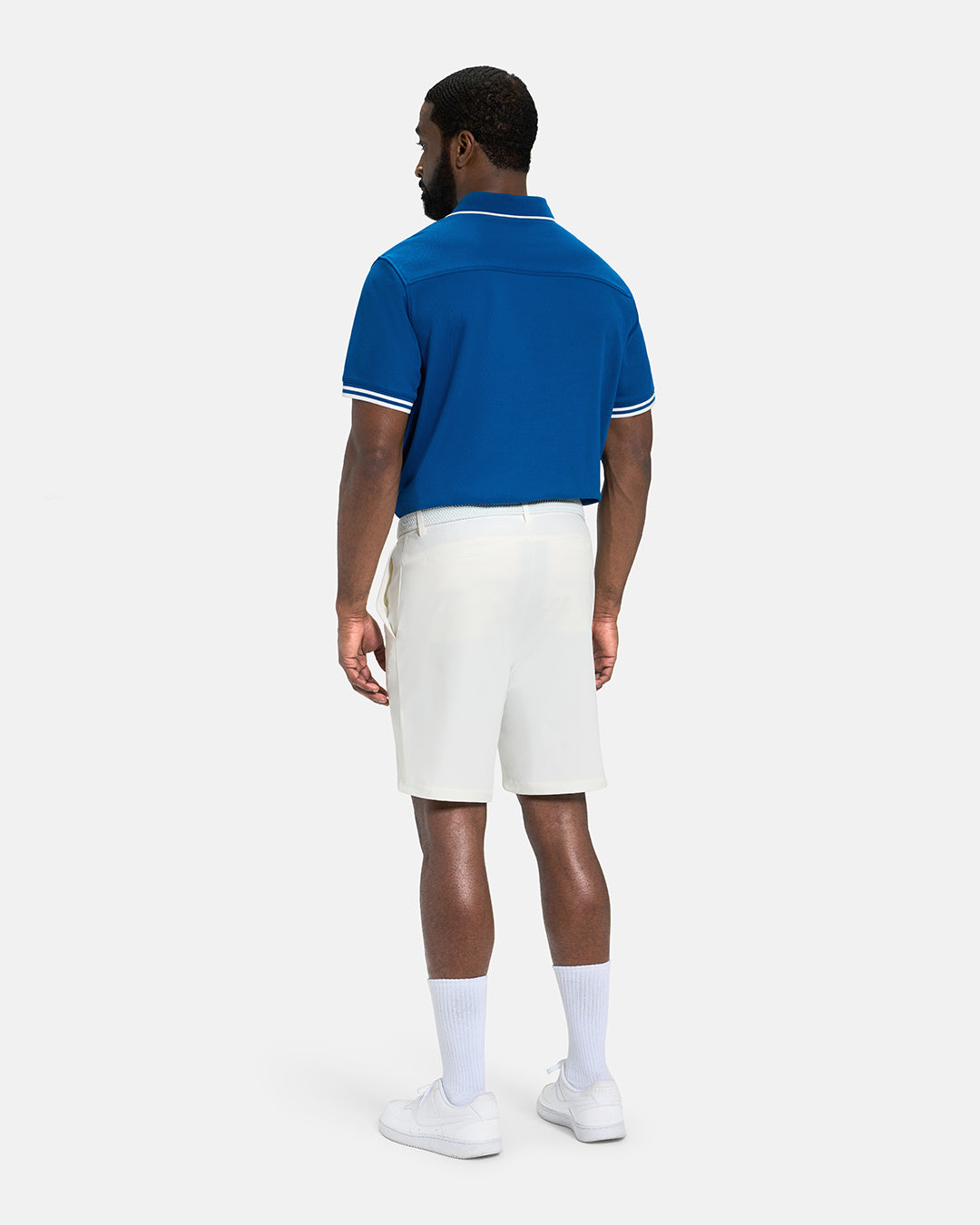 Full Body Back View of Royal Blue Spectator Tipped Collar Polo Tucked on Black Male Model wearing white shorts white belt and white shoes #color_royal-blue