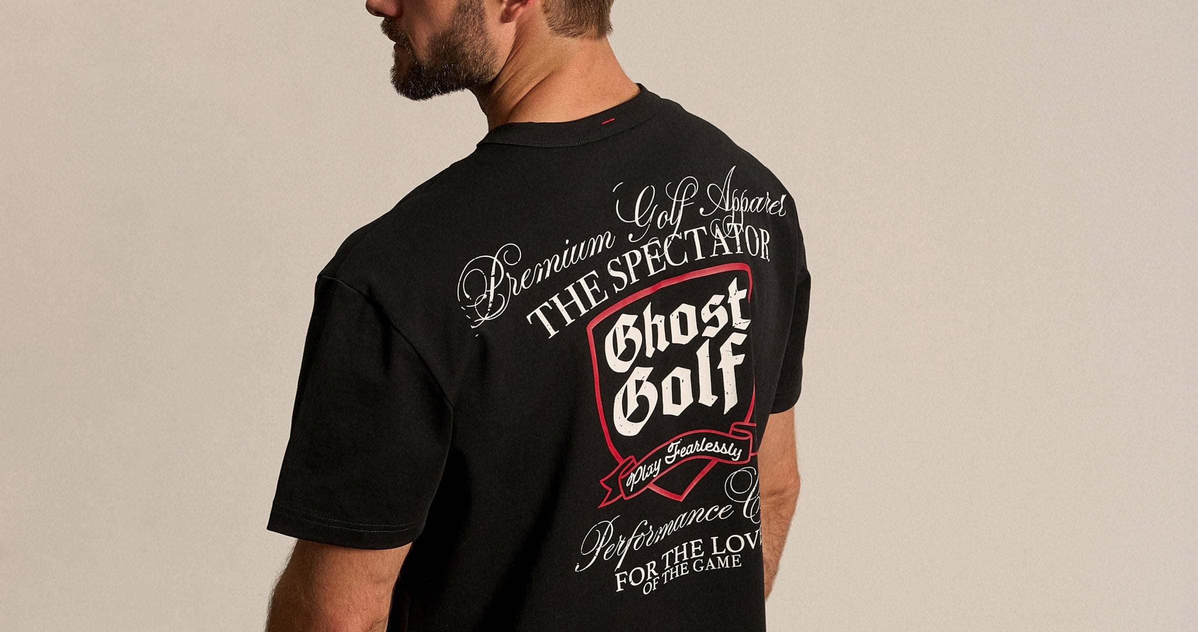White Male in studio, back facing, wearing a black Ghost Golf graphic tee.