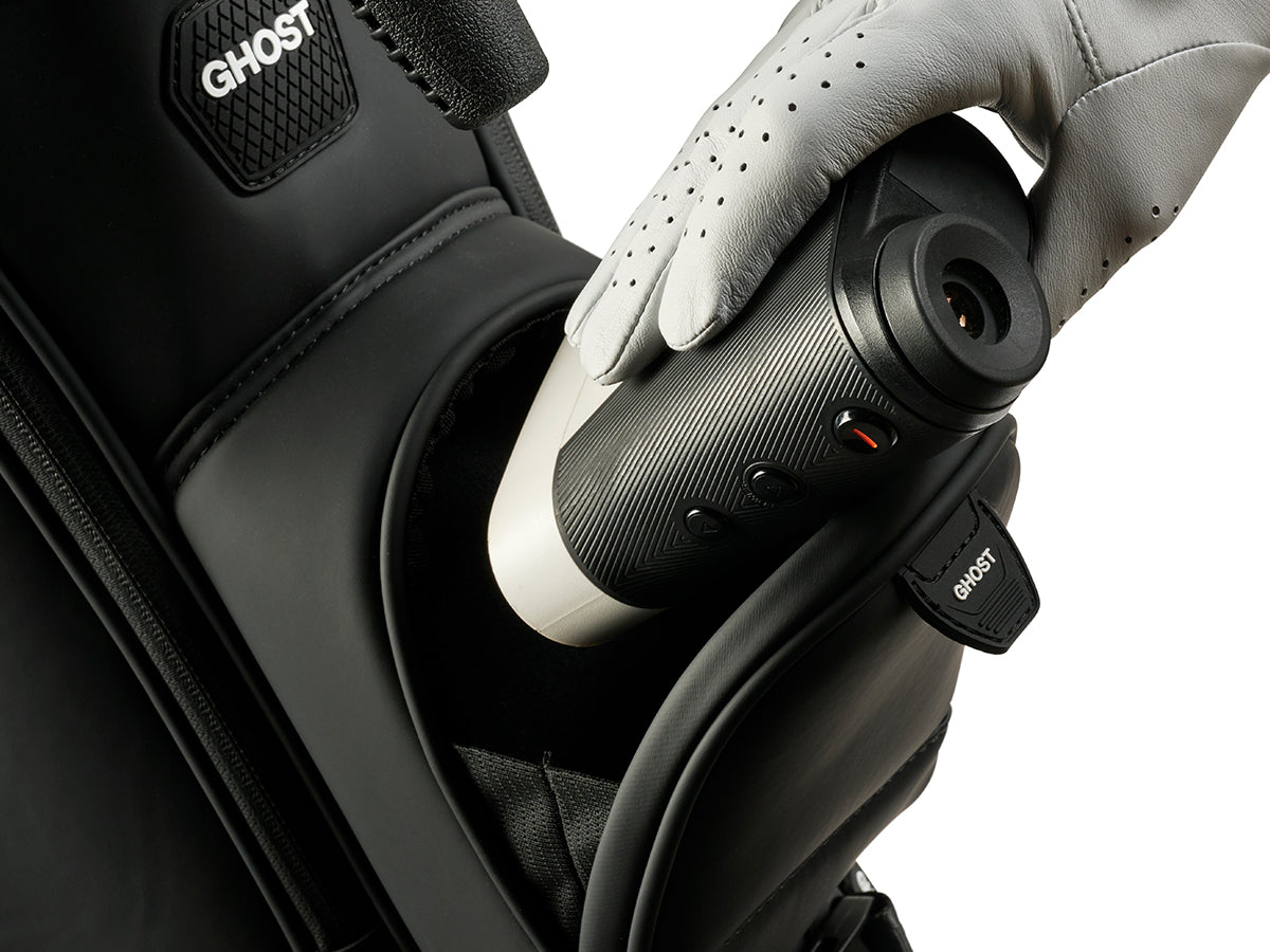 Close-up of a Range finder put inside the golf bag held by a gloved hand.