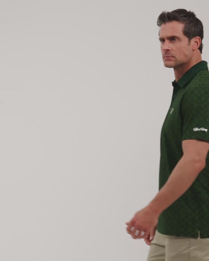 Male model walking naturally showcasing Bogey Green Patrons Printed Polo from all angles wearing beige pants and white shoes #color_bogey-green